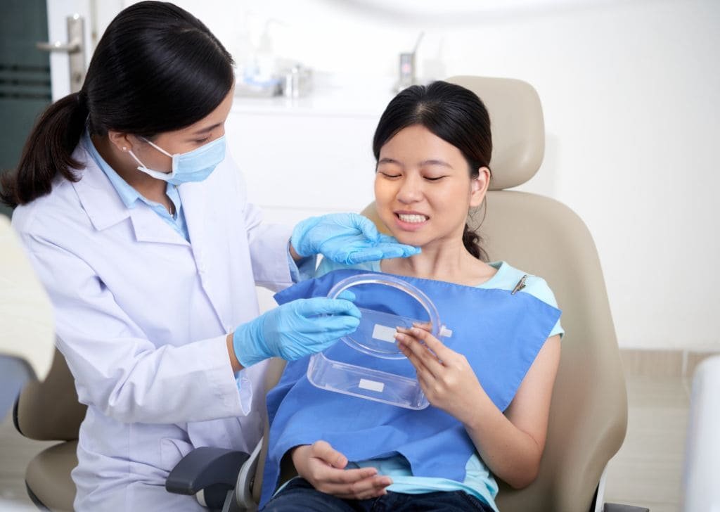 Female patient inspecting her teeth with a dentist before getting braces. 